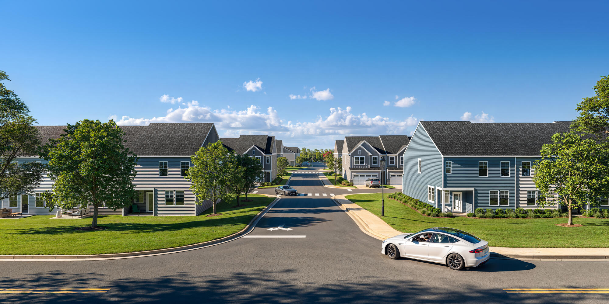 A white car is parked on the right side of a street in a residential neighborhood.